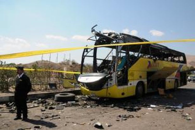 Seorang petugas kepolisian Mesir menjaga puing-puing bus wisata yang dibom di kota Taba, Sinai, Minggu (16/2/2014). Insiden itu menewaskan dua turis Korea Selatan dan seorang warga Mesir.

