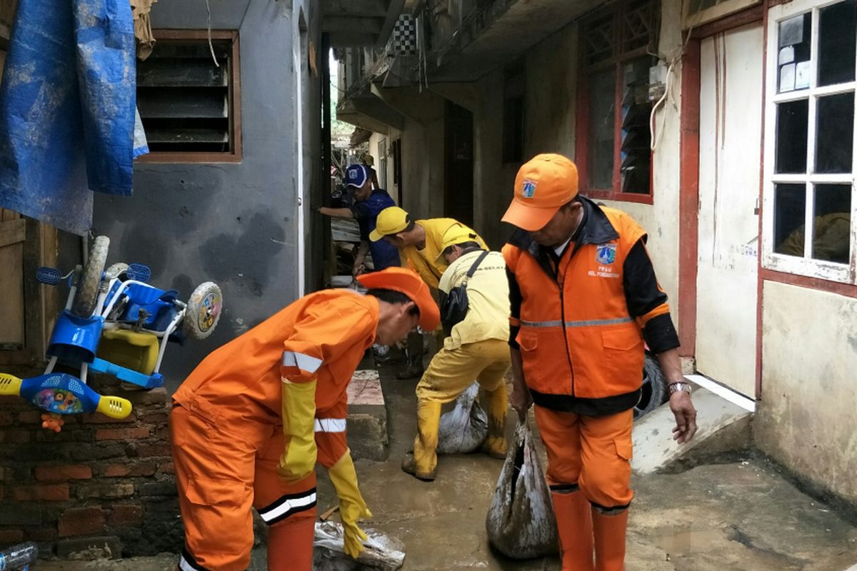 Pasukan oranye, biru, kuning, dan hijau bahu membahu membersihkan lumpur pasca-banjir luapan Ciliwung di permukiman warga Kelurahan Pengadegan, Pancoran, Jakarta Selatan, Senin (12/2/2018).