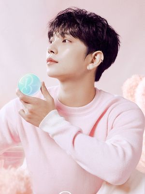 Joshua Hong mengenakan sweater pink pastel.