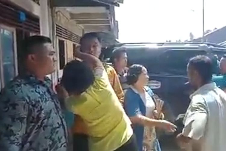 seorang ibu berusaha melindungi mantan Bupati Nias Selatan Idealisman Dachi, usai terjadi pelemparan dengan kotoran babi yang hampir mengenai dirinya, saat menghadiri acar syukuran atas pemenangan Kepala Desa Hilisatoro Gewa, atas nama Wisnu Duha, Kecamatan Toma, Kabupaten Nias Selatan, Sumatera Utara, Sabtu (25/1/2020) siang.