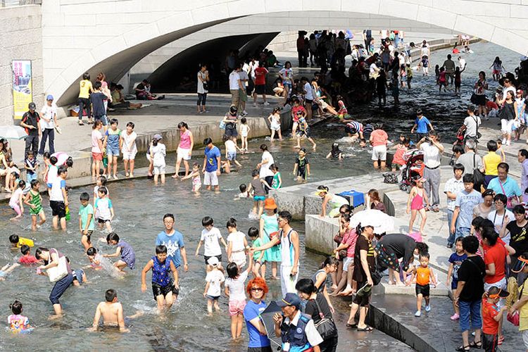 Warga Korea Selatan menikmati kesejukan di aliran Cheonggyecheon di tengah teriknya musim panas.