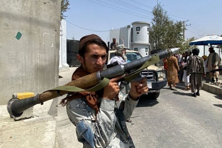 Seorang petempur Taliban dengan senjatanya di depan kantor Kementerian Dalam Negeri di ibu kota Kabul, Selasa (17/8/2021).
