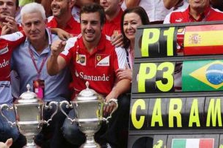 Pebalap Ferrari, Fernando Alonso (tengah), diapit ayah Jose Luiz dan ibu Ana Diaz, berpose bersama Felipe Massa (kiri) dan tim Ferrari, setelah berhasil finis pertama di sirkuit Catalunya pada GP Spanyol, Minggu (12/5/2013).