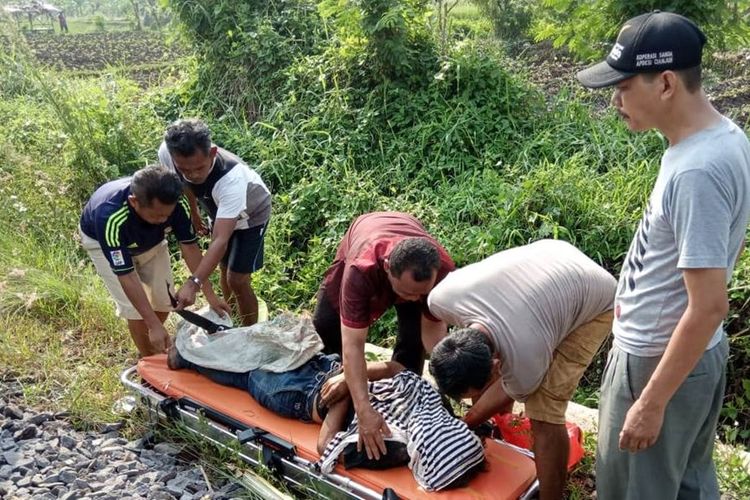 Sejumlah warga tengah mengevakuasi jenazah Mamat (59), warga Kabupaten Cianjur, Jawa Barat yang tewas usai tertabrak kereta api, Selasa (03/12/2019).