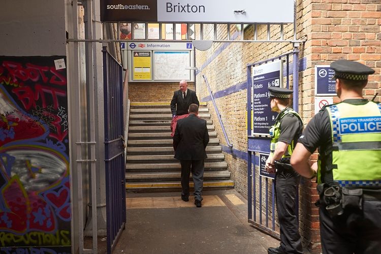 Petugas mengangkut jenazah satu dari tiga korban yang ditemukan telah tak bernyawa di sekitar lintasan kereta api di dekat Stasiuh Brixton, London selatan, Senin (18/6/2018).