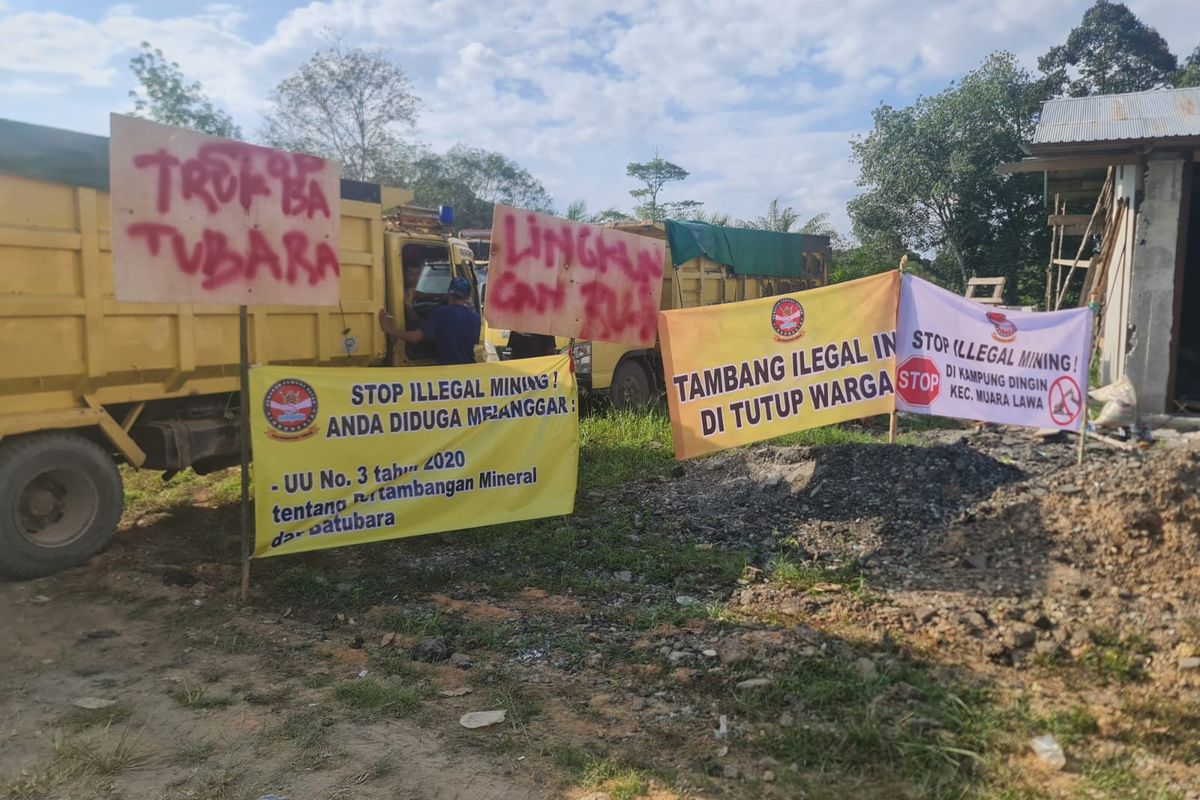 Warga memasang spanduk tolak tambang ilegal di areal lahan parkir truk-truk yang ditahan warga di Kampung Dingin, Kutai Barat, Kaltim, Rabu (28/9/2022).