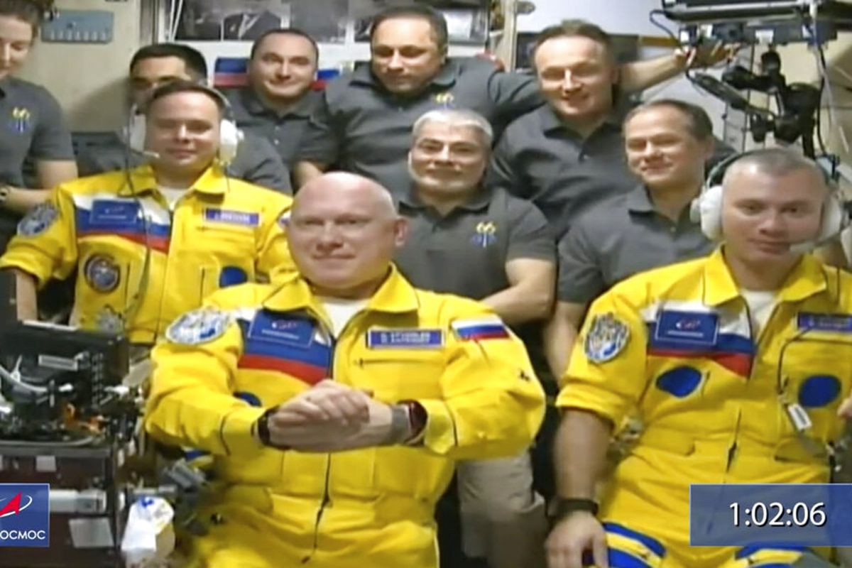 Kosmonot Rusia Sergey Korsakov, Oleg Artemyev dan Denis Matveyev terlihat mengenakan setelan penerbangan kuning dengan garis-garis biru, warna bendera Ukraina, selama upacara penyambutan setelah tiba di Stasiun Luar Angkasa Internasional, Jumat (18/3/2022).