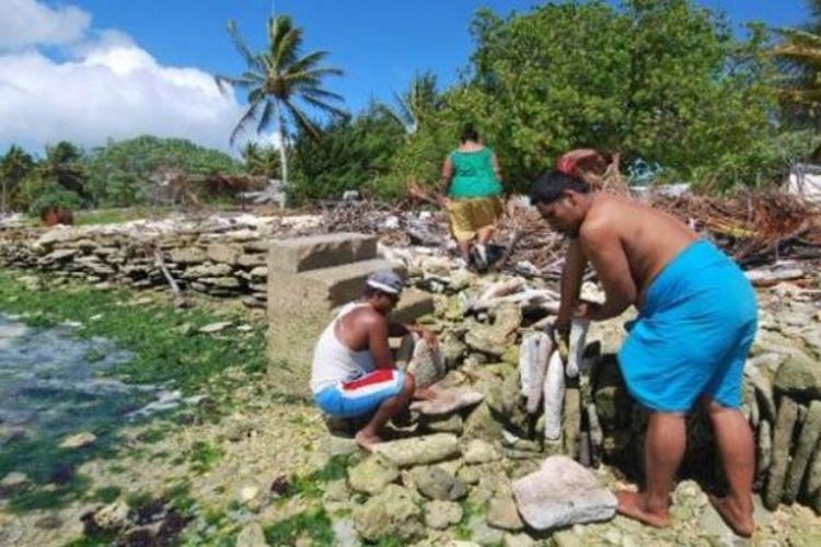 Foto ini menampilkan warga pulau Kiritimati, Kiribati tengah membangun tembok laut untuk mengurangi dampak ombak samudera Pasifik ke daratan. Kiribati adalah negara kepulauan kecil di Pasifik yang ketinggian rata-rata wilayah daratnya hanya beberapa meter di atas permukaan air laut. Akibat perubahan iklim, permukaan air laut meningkat dan membahayakan kehidupan di pulau-pulau kecil semacam Kiribati.