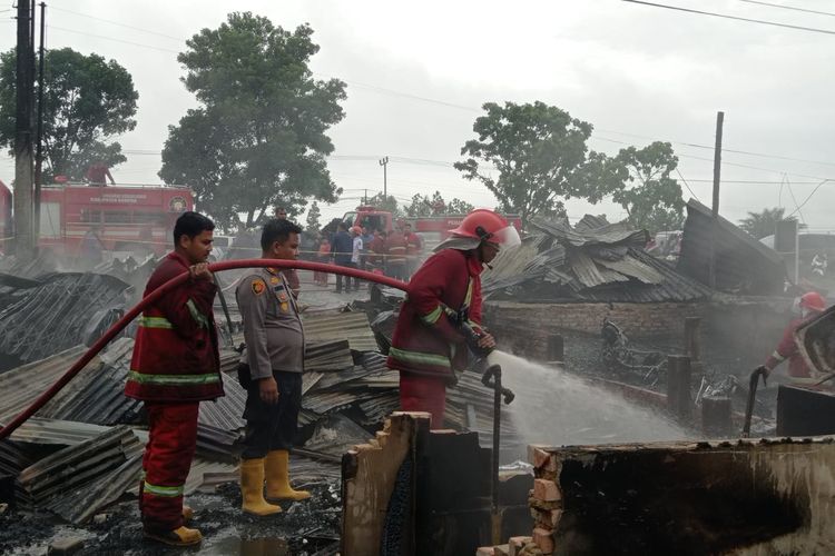 Petugas saat memadamkan enam kios yang terbakar di Desa Rimbo Panjang, Kecamatan Tambang, Kabupaten Kampar, Riau, Rabu (22/5/2024).
