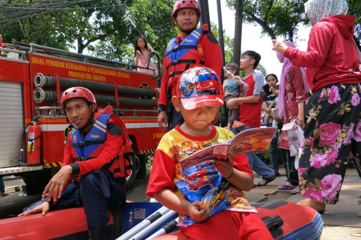 Seorang anak melihat komik pemadam kebakaran sambil duduk di atas perahu karet di Festival Bongsang yang digelar di Jalan Raya Ragunan, Jatipadang, Pasar Minggu, Jakarta Selatan, Minggu (25/3/2018).