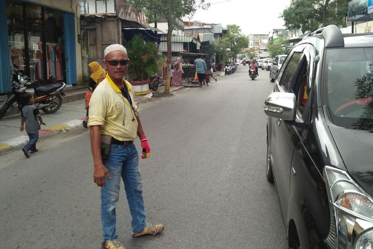 Iskandar Si Juru Parkir saat mengatur kendaraan di Jalan PRA Kusumayudha, Pangkalan Bun, 12 Juli 2019