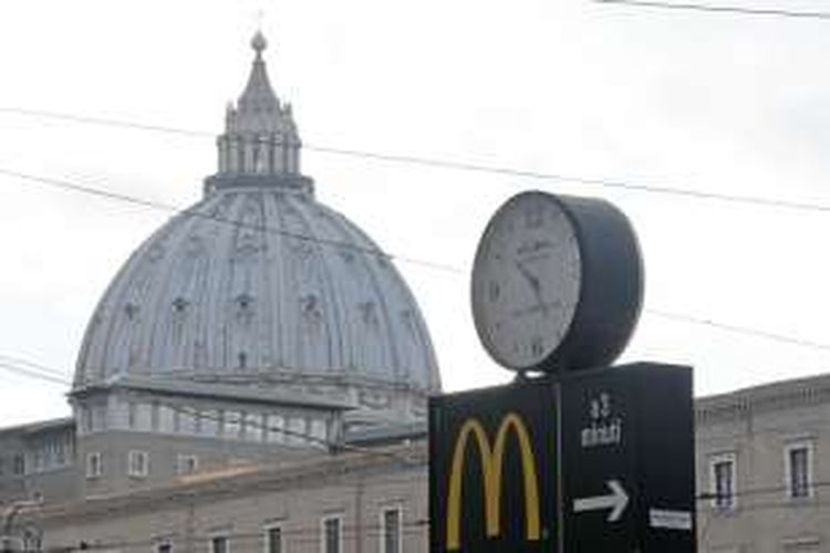 Lambang restoran cepat saji McDonald's dengan latar belakang kubah Basilika Santo Petrus, Vatikan.