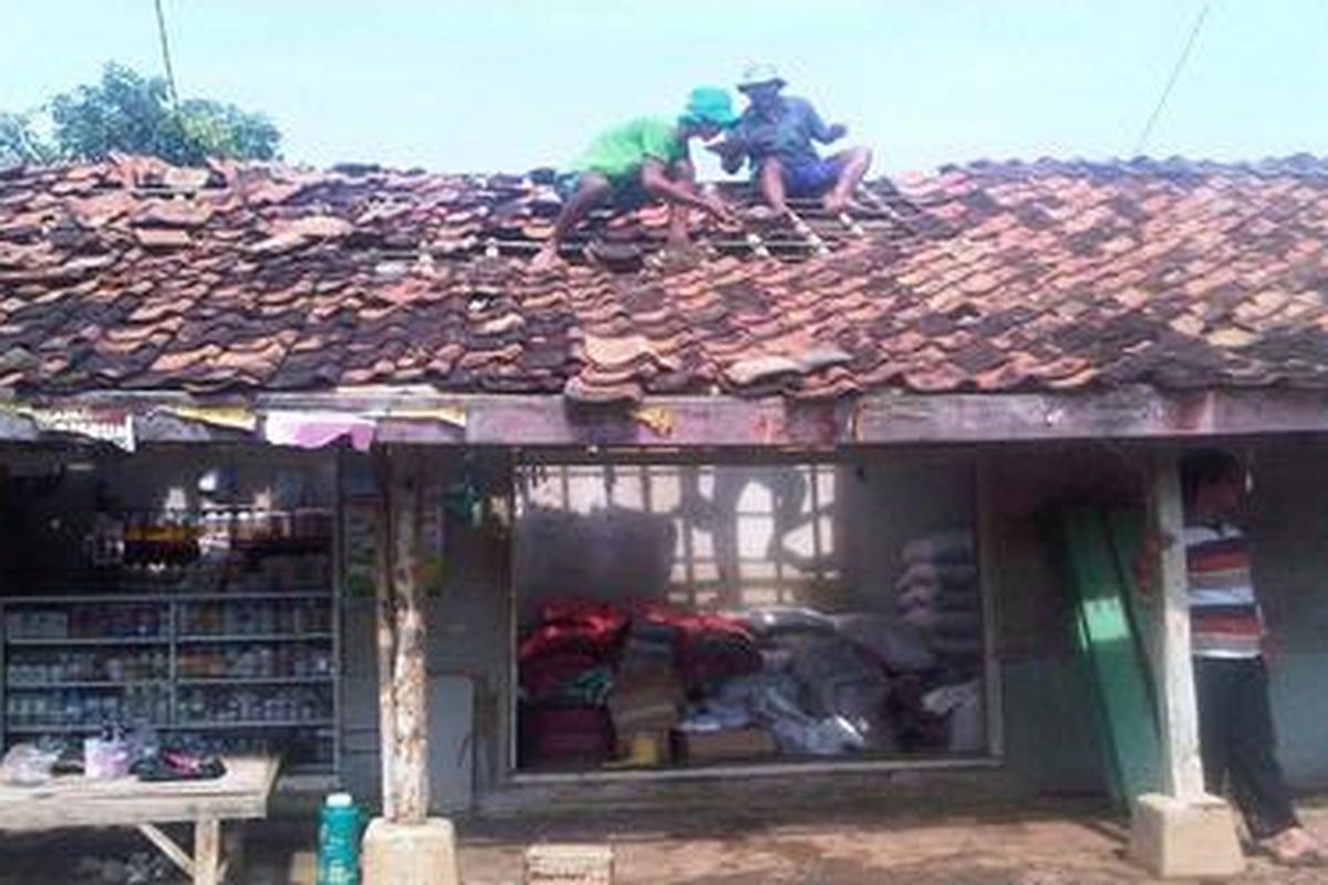 Beberapa warga membetulkan genteng yang berserak akibat angin kencang di Desa Peringkasap, Kecamatan Pabuaran, Kabupaten Subang, Jawa Barat, Kamis (9/2/2012).   