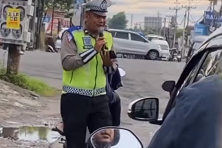 Tangkapan layar video yang memperlihatkan aksi seorang anggota polisi bernyanyi diiringi gitar akustik dari seorang pengamen jalanan saat bertugas.