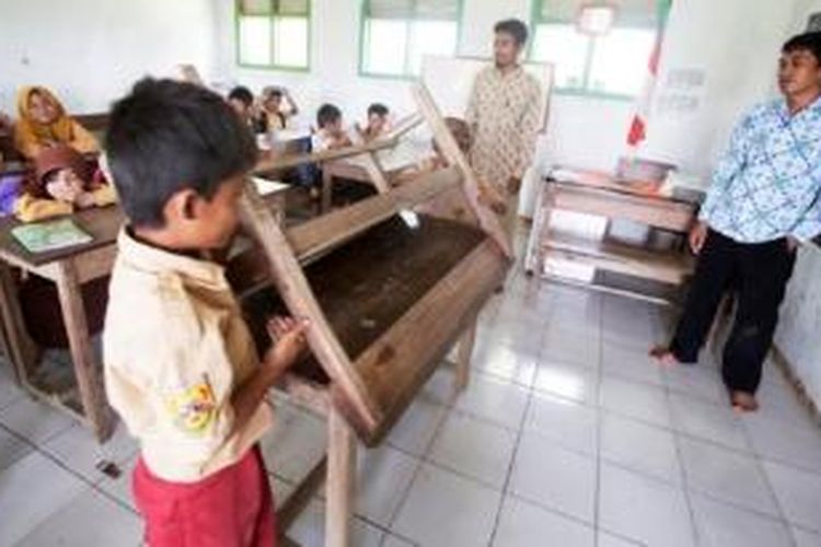 Murid-murid merapikan bangku dan kursi sebelum pulang di SDN Caringin, Tegalbuleud, Sukabumi, Jumat (20/11).