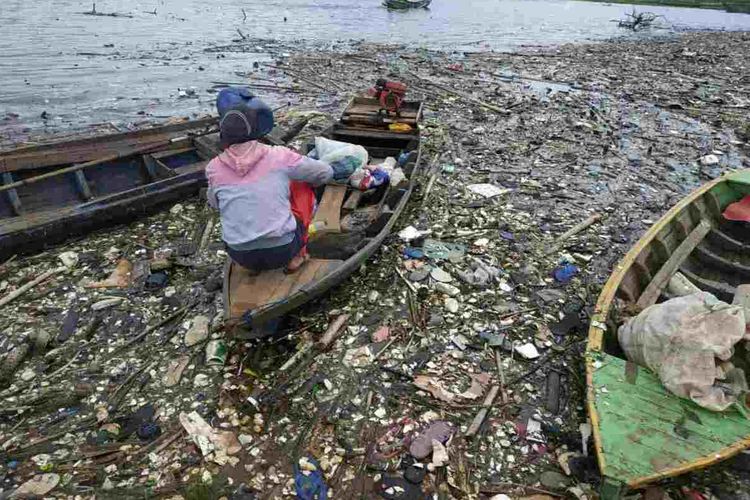 Warga Wado, Sumedang, Jawa Barat memilah sampah plastik di antara lautan sampah yang mengotori pesisir Waduk Jatigede, Selasa (2/2/2021) pagi. AAM AMINULLAH/KOMPAS.com