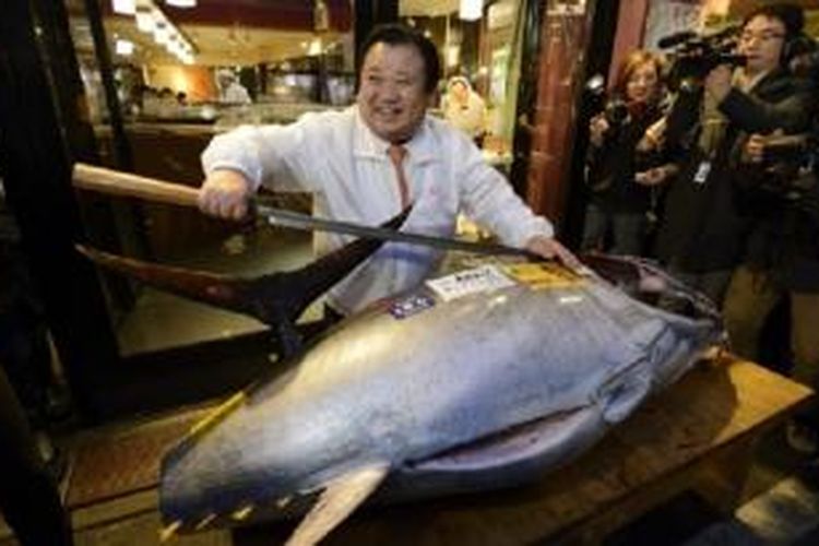 Kiyoshi Kimura, Presiden Kiyomura KK, berpose dengan ikan tuna seberat 180 kilogram, yang dibeli seharga 4,51 juta yen dalam lelang tahun baru tahunan di pasar ikan Tsukiji, Tokyo, Senin (5/1/2015).