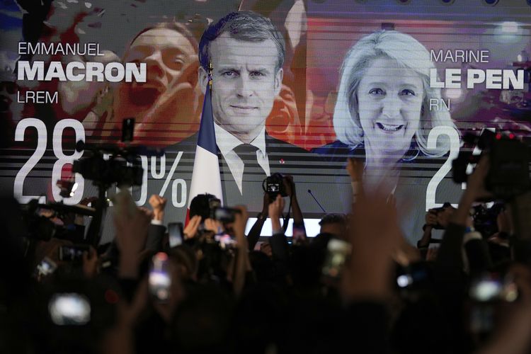 Layar menampilkan wajah petahana Emmanuel Macron (kiri) dan Marine Le Pen yang berlaga di Pilpres Perancis 2022. Gambar diambil di Paris, Perancis, Minggu (10/4/2022). 
