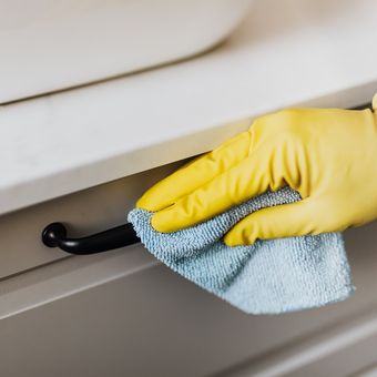 Ilustrasi membersihkan gagang lemari dengan disinfektan. 