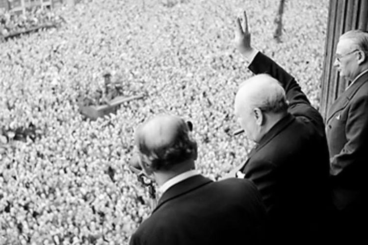 PM Inggris Winston Churchill melambaikan tangan kepada warga London yang tumpah ruah di jalanan setelah Perang Dunia II di Eropa dipastikan berakhir.