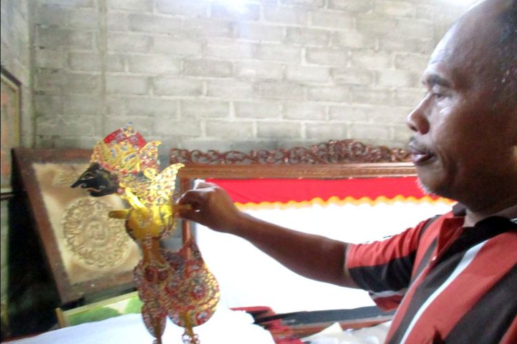 Seorang perajin sedang menunjukkan wayang yang belum selesai diproses.