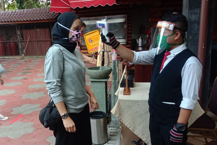 Karyawan Resto Bumi Aki Bogor melakukan pengecekan suhu tubuh terhadap seorang pengunjung yang datang, Selasa (2/6/2020). Pemerintah Kota (Pemkot) Bogor telah memberi kelonggaran restoran maupun rumah makan untuk beroperasi kembali selama PSBB dengan catatan memperhatikan protokol kesehatan.