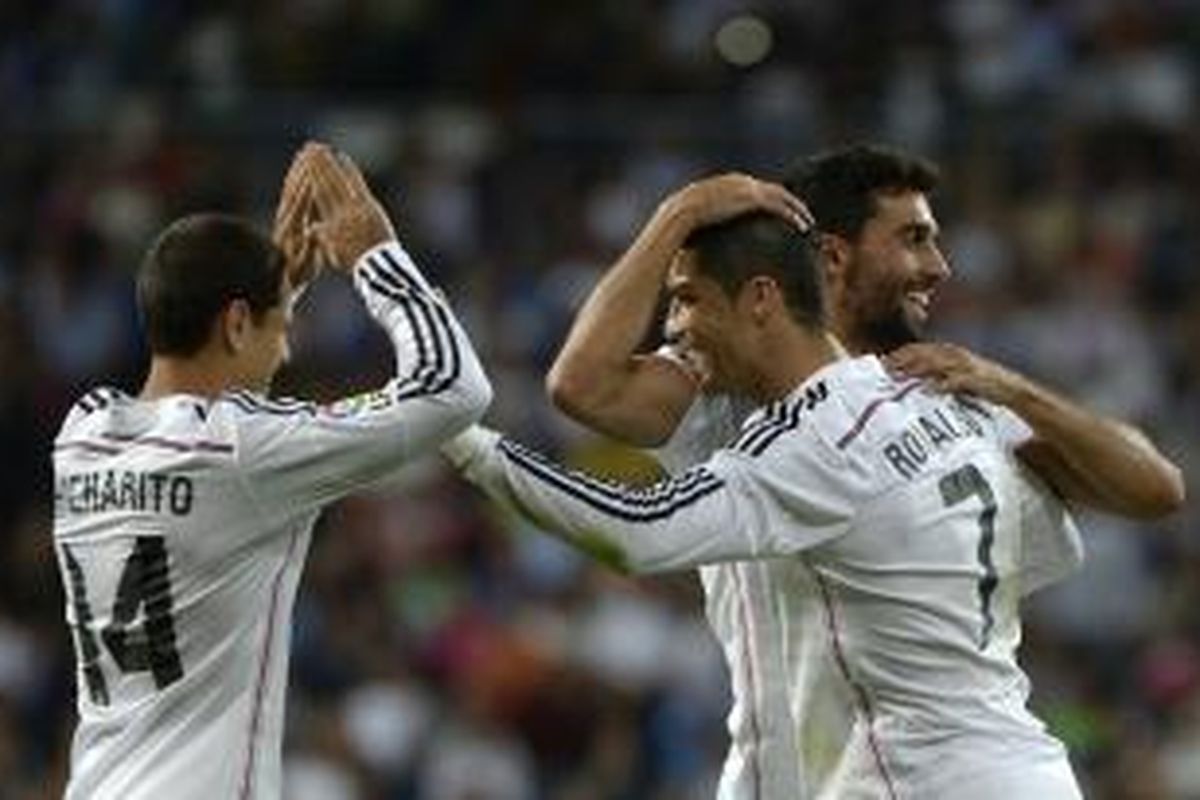 Gelandang Real Madrid, Cristiano Ronaldo (tengah), merayakan gol ketiganya (dari empat) ke gawang Elche, dengan Javier Hernandez (kanan) dan Albaro Arbeloa, pada laga Primera Division, di Santiago Bernabeu, Madrid, Selasa (23/9/2014).
