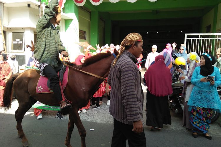 Salikun memegangi kuda miliknya tanpa delman, saat pawai siswi MINU Tratee Putri Gresik menyambut tahun baru hijriyah dan momen Agustusan, Jumat (12/8/2022). *** Local Caption *** Salikun memegangi kuda miliknya tanpa delman, saat pawai siswi MINU Tratee Putri Gresik menyambut tahun baru hijriyah dan momen Agustusan, Jumat (12/8/2022).