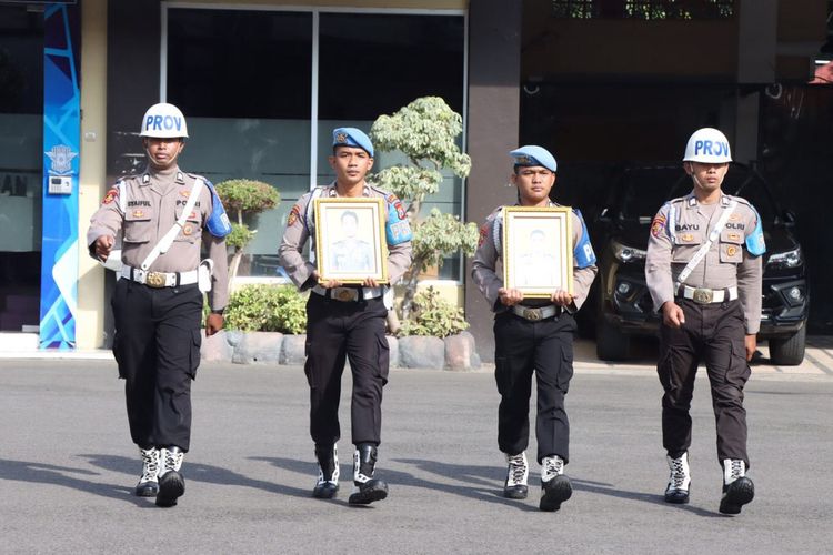 Petugas membawa foto dua personel Polres Lamongan yang diberhentikan dengan tidak hormat, yang tidak hadir dalam upacara di halaman Mapolres Lamongan, Jawa Timur.