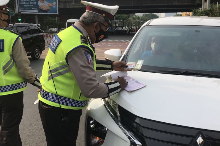 Anggota kepolisian memberikan sanksi berupa tilang untuk sejumlah pengendara mobil yang melanggar sistem ganjil genap di Jalan RS Fatmawati, Cilandak, Jakarta Selatan pada Senin (25/10/2021) pagi.