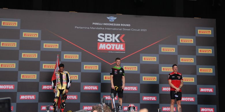 Pebalap Kawasaki Jonathan Rea (tengah) berdiri di podium Sirkuit Mandalika dengan diapit pebalap Yamaha Toprak Razgatlioglu (kiri) dan pebalap Ducati Scott Redding (kanan) usai Race 1 kelas World Superbike (WSBK) yang dihelat Minggu (21/11/2021). Meski memenangi balapan, Rea gagal mempertahankan gelar juara dunia yang sudah enam tahun beruntun ia raih.