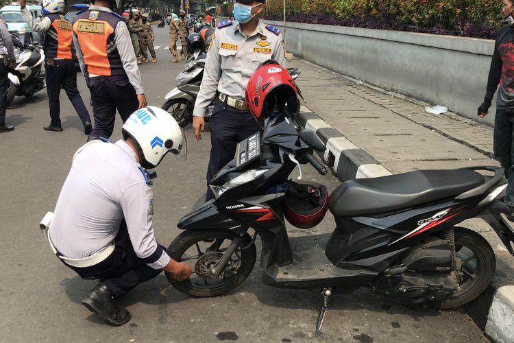 Anggota Suku Dinas Perhubungan Jakarta Selatan mencabut pentil ban motor yang ditemukan memarkirkan kendaraannya secara liar di sekitar Apartemen Kalibata City, Pancoran, Jakarta Selatan pada Senin (11/10/2021) siang.