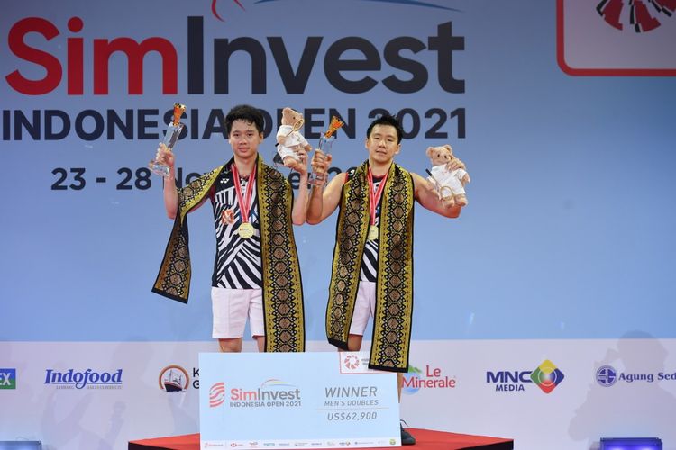 Kevin Sanjaya Sukamuljo (kiri) dan Marcus Fernaldi Gideon (kanan) saat mengangkat trofi juara Indonesia Open 2021 di Bali International Convention Centre, Minggu (28/11/2021).