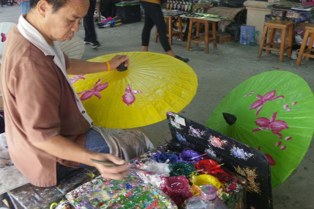 Seorang pekerja sedang melukis payung di tempat kerajinan Borsang, Chiang Mai, Thailand, Rabu (14/6/2017). 