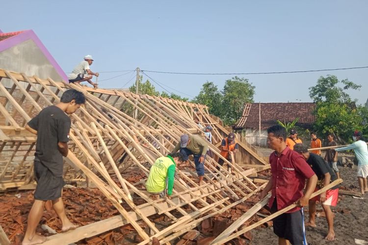 Nampak warga bergotong royong membantu memperbaiki rumah warga Desa Tulung, Kecamatan Saradan yang ambruk diterjang hujan disertai angin kencang.