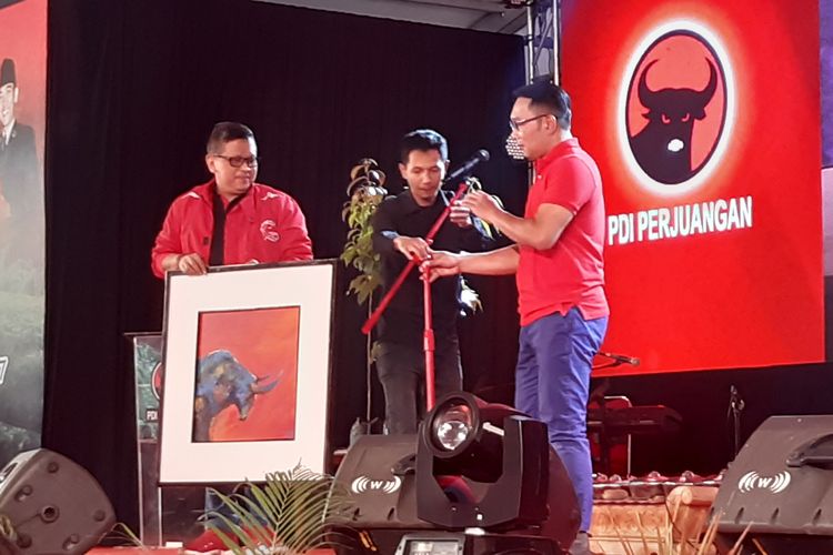 Gubernur Jawa Barat Ridwan Kamil menyerahkan lukisan bergambar banteng kepada Sekjen PDI-P Hasto Kristiyanto.