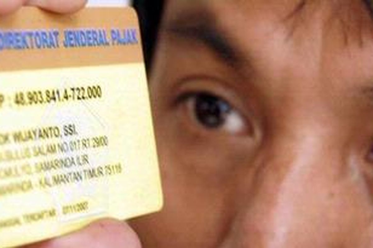 Seorang wajib pajak memegang kartu No Pokok Wajib Pajak (NPWP) sistem online di Jakarta.