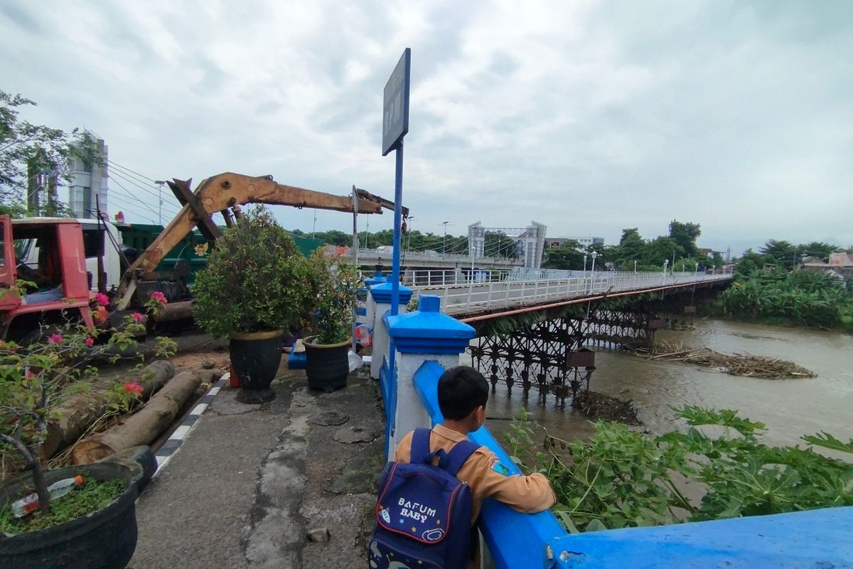 Seorang siswa melihat aktifitas pembersihan sampah di areal Jembatan Lama Kota Kediri, Jawa Timur, Jumat (31/1/2025).