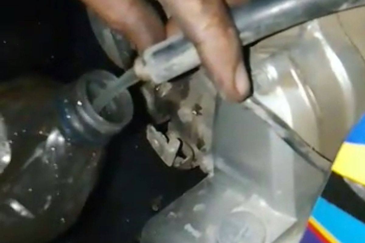 Salah satu pengendara mengeluarkan bahan bakar minyak dari tangki kendaraannya karena mogok usai mengisi BBM di SPBU kawasan Pesanggaran Banyuwangi. BBM tersebut diduga bercampur dengan air.