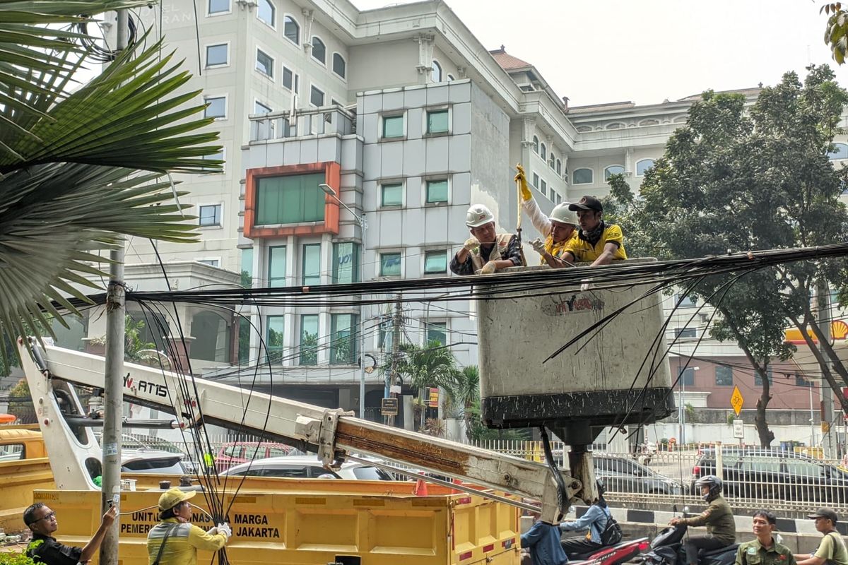 Petugas Suku Dinas (Sudin) Bina Marga Jakarta Selatan menertibkan kabel fiber optik yang semrawut sepanjang 5,4 kilometer di Kecamatan Mampang Prapatan pada Senin (8/5/2023). 
