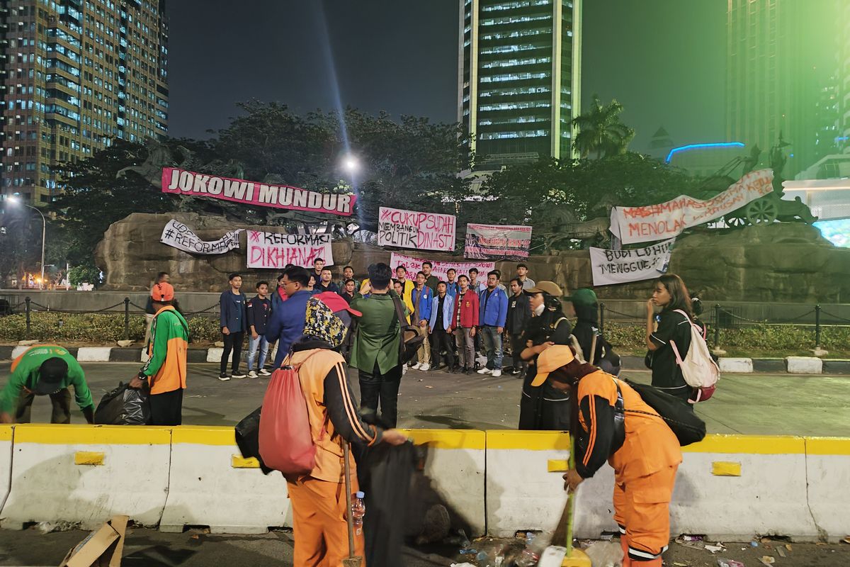 Sejumlah mahasiswa berfoto di depan Patung Kuda yang tergantung spanduk usai demo berakhir di Jalan Medan Merdeka Barat, Gambir, Jakarta Pusat, Jumat (20/10/2023). (KOMPAS.com/XENA OLIVIA)
