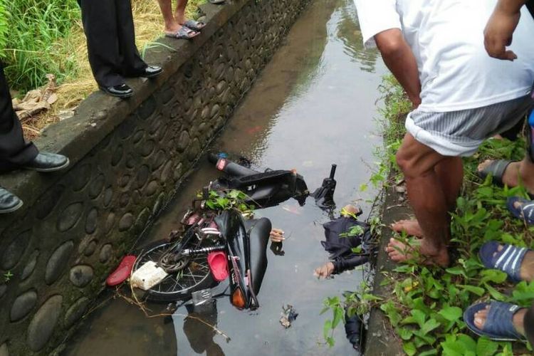 Bersama polisi, warga mengevakuasi mayat pria yang ditemukan di saluran irigasi bersama sepeda motornya di jalan poros Barombong - Panciro, Kabupaten Gowa, Sulawesi Selatan. Selasa, (20/6/2017).