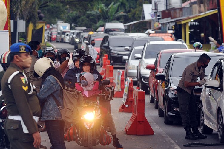 Kendaraan roda empat antre memasuki kota saat masa PSBB, di Posko Perbatasan Kayukalek, Padang, Sumatera Barat, Selasa (26/5/20). Pasca libur Lebaran, banyak kendaraan terutama roda empat yang masuk ke kota Padang karena habis berlebaran dari luar kota seiring dengan kembali bekerjanya PNS di kota itu, namun tetap dilakukan pemeriksaan sesuai aturan PSBB.