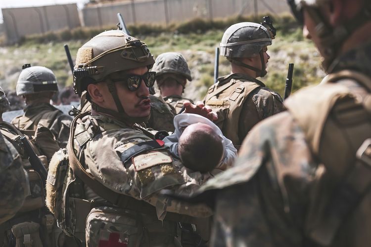 Foto dari Marinir AS memperlihatkan seorang personel Angkatan Udara Amerika Serikat menggendong bayi ketika melakukan evakuasi warga di bandara internasional Hamid Karzai, Kabul, Afghanistan, Jumat (20/8/2021).