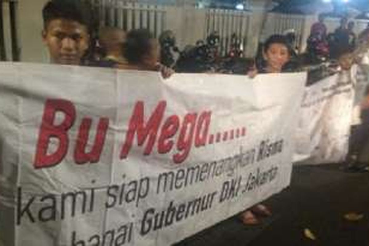 Pendukung Tri Rismaharini yang tergabung dalam Gerak Indonesia membentangkan spanduk dikungan agar Wali Kota Surabaya tersebut maju ke Pilgub Jakarta tahun depan, Kamis (21/7/2016) malam. 