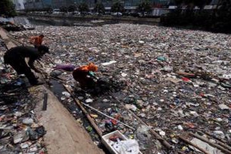 Petugas kebersihan berusaha menarik sampah yang kebanyakan limbah rumah tangga yang mencemari dan menutup aliran Kali Sunter di samping Jalan Danau Sunter Barat, Jakarta, Selasa (12/2/2013). Perilaku warga yang masih membuang sampah di sungai selain berpotensi menyumbat aliran juga menurunkan kualitas air sungai karena tercemar beragam limbah.

