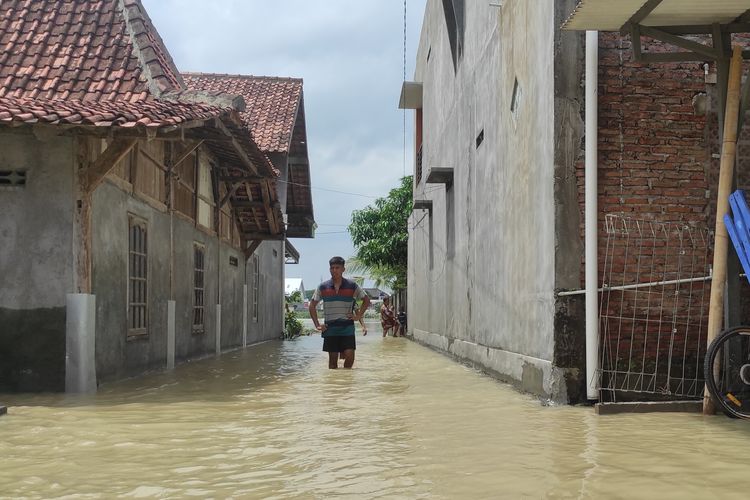 Seorang warga berjalan di genangan banjir Desa Sidorejo, Kecamatan Karangawen, Kabupaten Demak, Selasa (6/2/2024). (KOMPAS.COM/NUR ZAIDI).