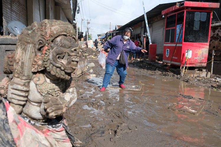 Warga berjalan melewati lumpur pasca terjadi banjir di Pasar Kumbasari, Denpasar, Bali, Kamis (11/9/2025).