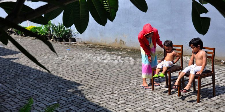 Seorang ibu menjemur kedua anaknya di bawah sinar matahari saat Self Isolation atau tinggal di rumah di Medan, Sumatera Utara, Minggu (22/3/2020). Berjemur diri di bawah matahari di antara pukul 08.00 WIB-11.00 WIB merupakan salah satu upaya yang paling sederhana untuk menjaga kesehatan selama wabah virus COVID-19.