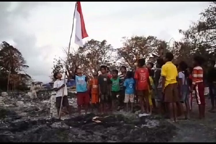 Anak-anak menancapkan tiang bendera dan memberikan hormat kepada Bendera Merah Putih di atas puing-puing rumah yang sudah hangus terbakar di Kampung Adat Situs Deke, Desa Patiala Bawah, Kecamatan Lamboya, Kabupaten Sumba Barat, Nusa Tenggara Timur (NTT). 